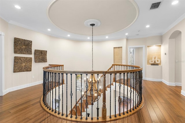 hallway with an upstairs landing, wood finished floors, and crown molding