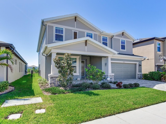 craftsman-style home featuring a garage, stone siding, a front lawn, and decorative driveway