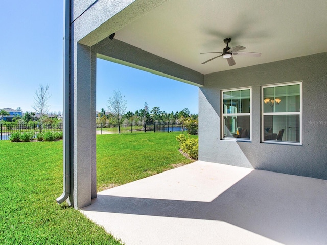 view of patio / terrace with a ceiling fan, a water view, and fence