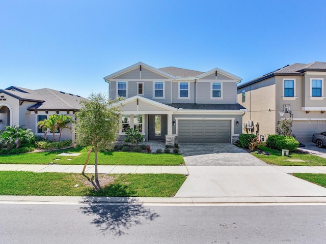 view of front of property featuring a front yard, decorative driveway, and an attached garage