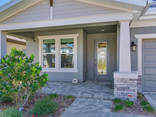 property entrance with covered porch and stucco siding