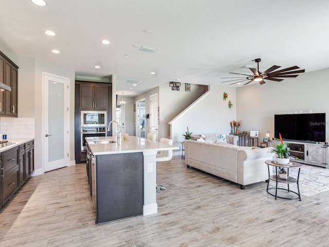 kitchen with open floor plan, stainless steel microwave, a sink, and backsplash