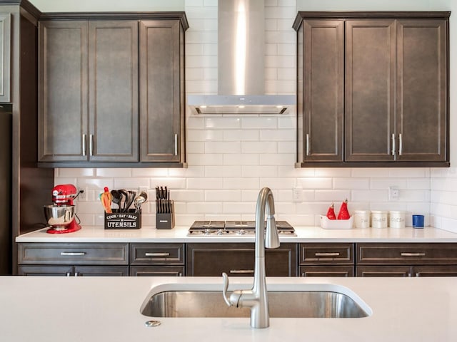 kitchen featuring tasteful backsplash, light countertops, dark brown cabinets, and wall chimney exhaust hood