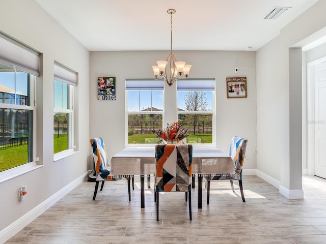 dining space with baseboards, light wood finished floors, visible vents, and an inviting chandelier