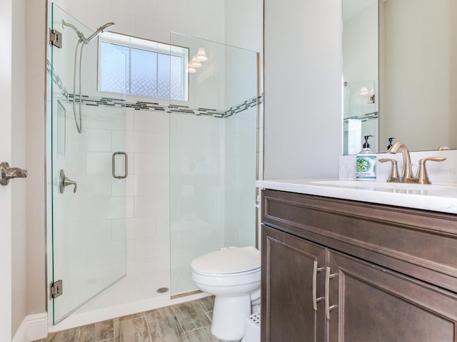 bathroom featuring toilet, a shower stall, vanity, and wood finished floors