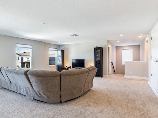living room featuring a textured ceiling, recessed lighting, light colored carpet, visible vents, and baseboards