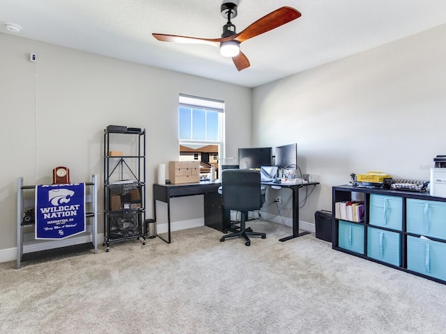 carpeted office space with ceiling fan and baseboards