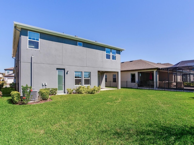 rear view of property with stucco siding, a lawn, and fence