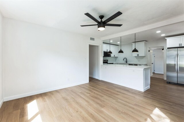 kitchen featuring stainless steel appliances, light countertops, a sink, and light wood finished floors