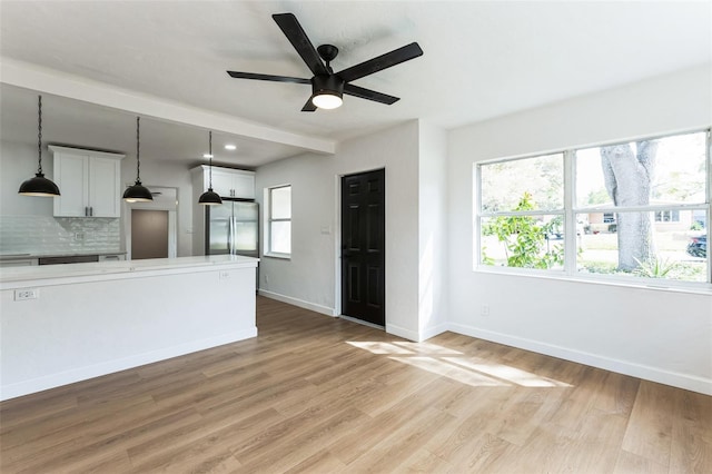 interior space featuring ceiling fan, light wood-style flooring, and baseboards