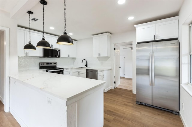 kitchen with a peninsula, a sink, white cabinetry, appliances with stainless steel finishes, and decorative backsplash