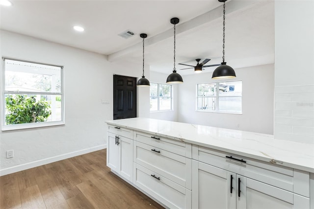 kitchen with light wood finished floors, visible vents, white cabinetry, light stone countertops, and baseboards