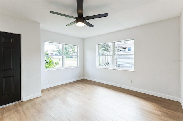 spare room featuring light wood-style flooring, baseboards, and ceiling fan