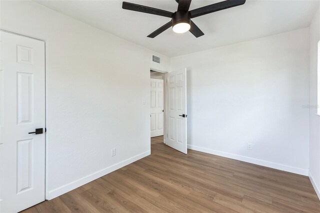 unfurnished bedroom featuring a ceiling fan, visible vents, baseboards, and wood finished floors