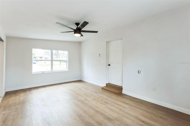 spare room featuring a ceiling fan, baseboards, and wood finished floors