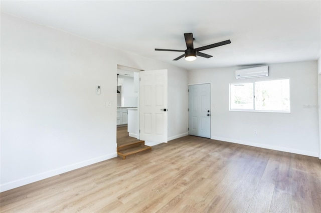 spare room featuring a wall unit AC, light wood-type flooring, and baseboards