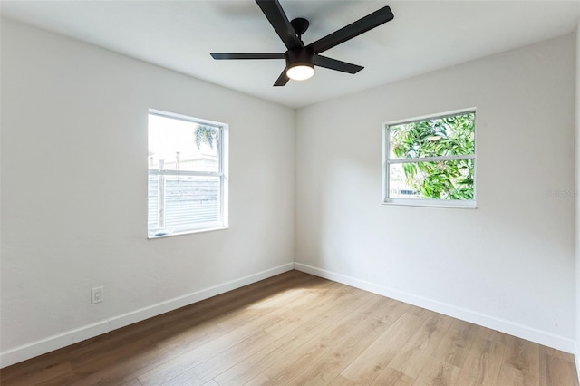 spare room featuring a healthy amount of sunlight, baseboards, and wood finished floors