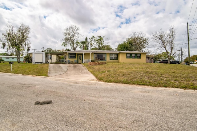 single story home featuring driveway, a storage shed, an outdoor structure, a carport, and a front yard