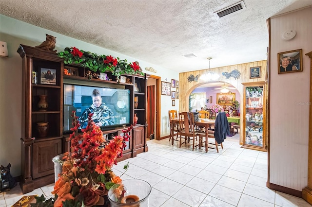 dining space featuring visible vents, arched walkways, a textured ceiling, and light tile patterned flooring