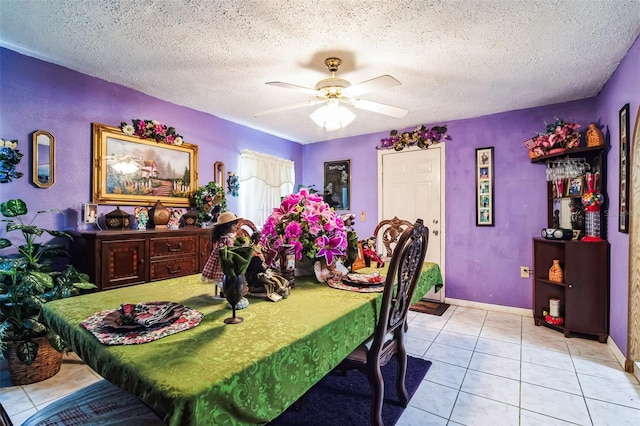 tiled dining space with ceiling fan, a textured ceiling, and baseboards