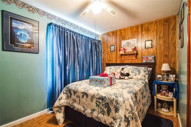 bedroom featuring a ceiling fan, wood walls, and baseboards