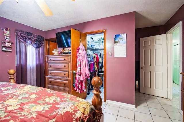 tiled bedroom featuring a textured ceiling, ceiling fan, a closet, and baseboards