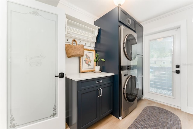 clothes washing area with crown molding, stacked washer and dryer, cabinet space, and light wood-style flooring