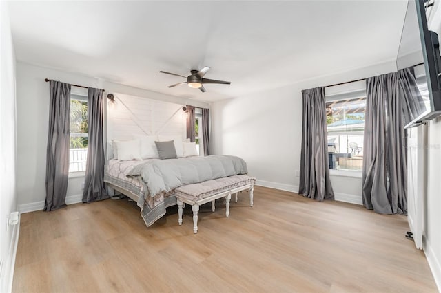 bedroom featuring a ceiling fan, baseboards, and light wood finished floors