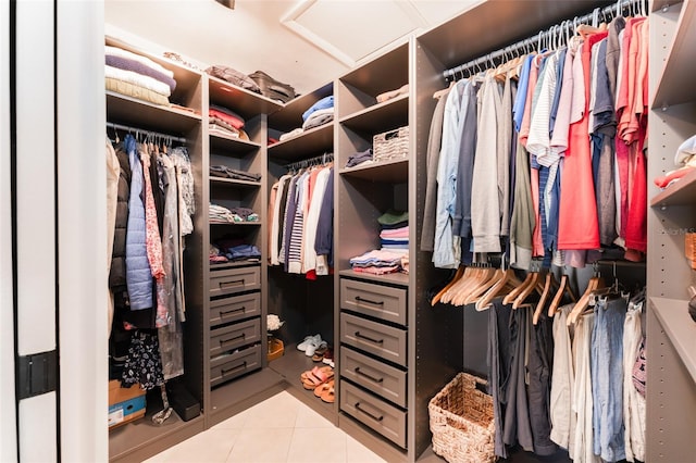 walk in closet featuring light tile patterned floors and attic access