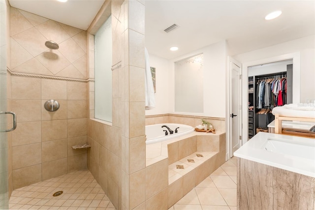 bathroom featuring visible vents, a walk in closet, a stall shower, a bath, and tile patterned floors