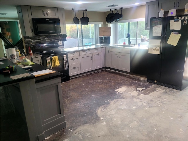 kitchen featuring a sink, visible vents, light countertops, backsplash, and black appliances