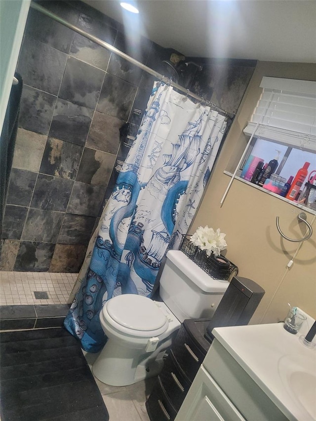 bathroom with tile patterned flooring, a tile shower, vanity, and toilet