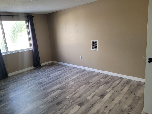 spare room featuring visible vents, baseboards, and wood finished floors