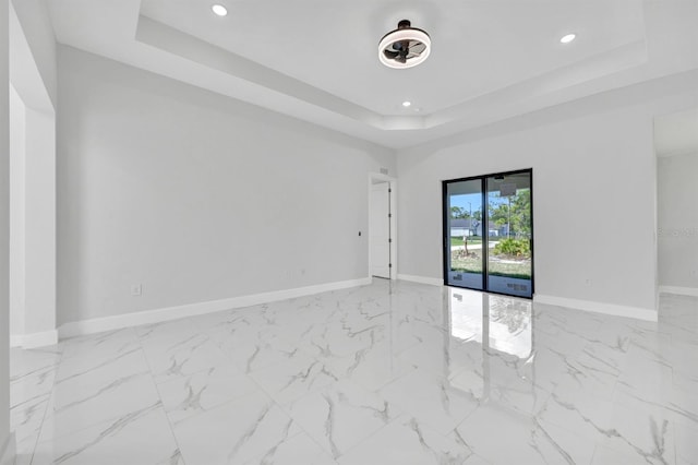 spare room with baseboards, a raised ceiling, and recessed lighting