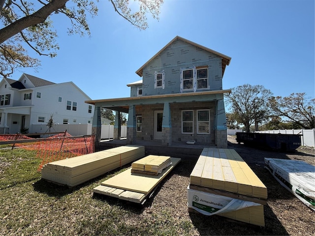 rear view of property with stone siding and fence