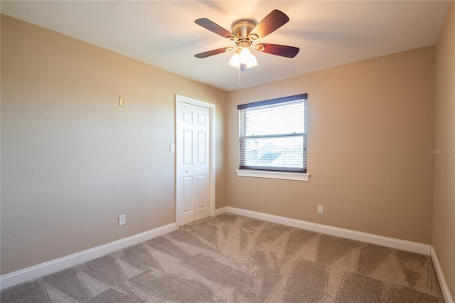 unfurnished room featuring baseboards, light colored carpet, and ceiling fan