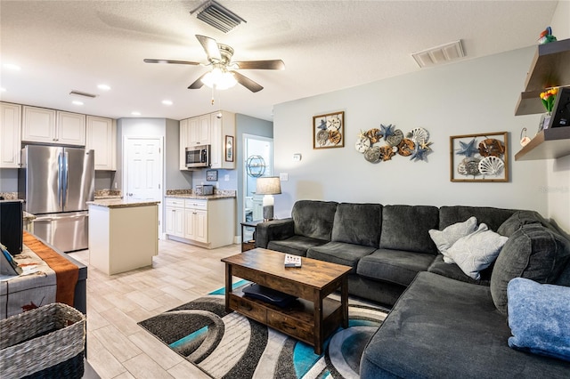 living area featuring visible vents, ceiling fan, and light wood finished floors