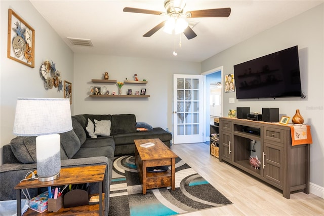 living room with light wood-style flooring, a ceiling fan, and visible vents