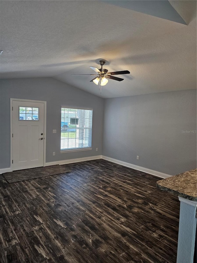 unfurnished living room featuring lofted ceiling, a textured ceiling, dark wood finished floors, and baseboards