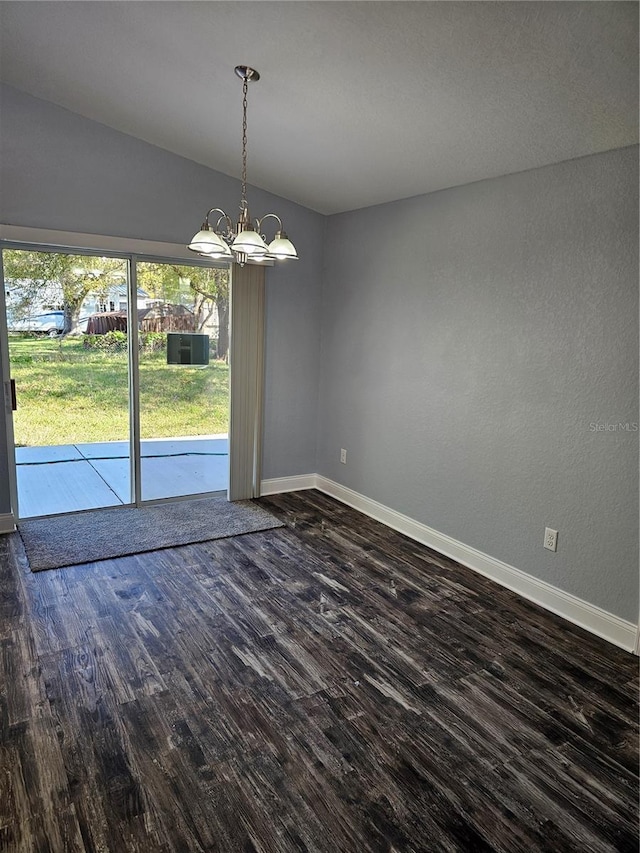 unfurnished dining area featuring dark wood-style floors, baseboards, and a notable chandelier