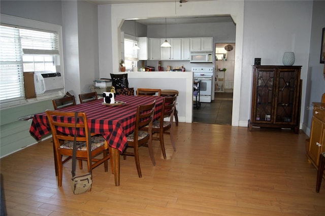 dining space featuring light wood-type flooring, arched walkways, and cooling unit