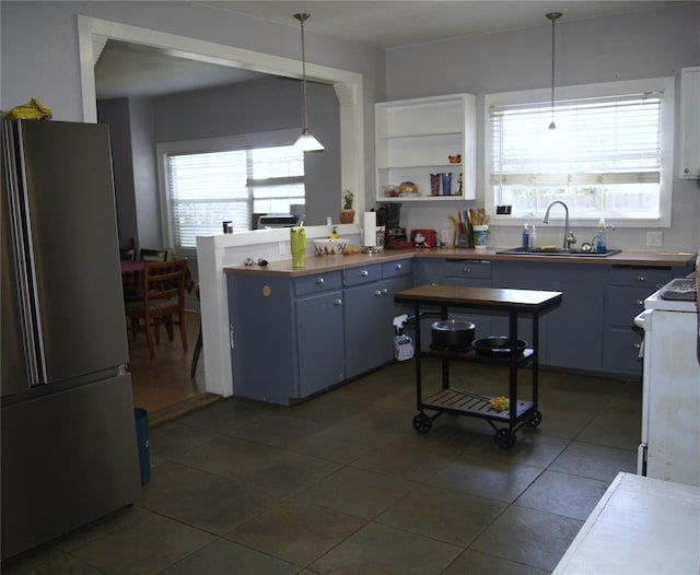 kitchen featuring white electric range, a sink, freestanding refrigerator, and a healthy amount of sunlight