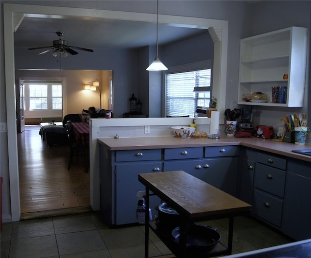 kitchen featuring open floor plan, a peninsula, tile patterned flooring, light countertops, and blue cabinetry