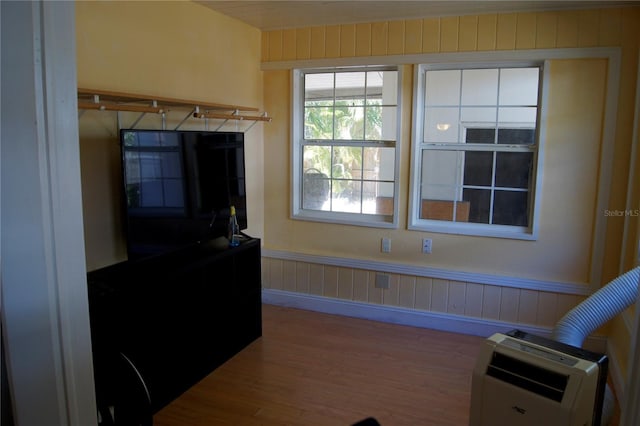 living area featuring heating unit, wood finished floors, and wainscoting