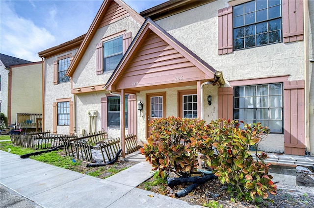 townhome / multi-family property featuring a porch, fence, and stucco siding