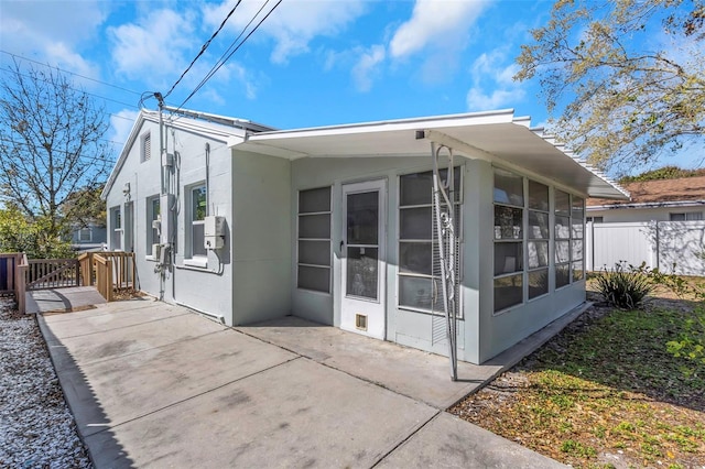 back of property featuring a patio area, fence, a sunroom, and stucco siding