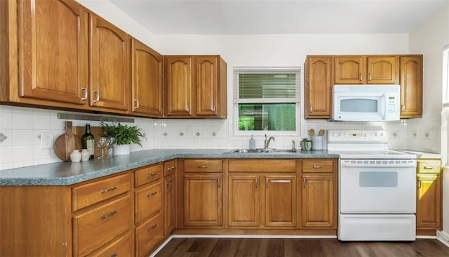 kitchen featuring white appliances, dark wood-style flooring, a sink, and brown cabinets