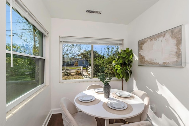 dining room featuring baseboards, visible vents, a wealth of natural light, and wood finished floors