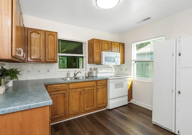 kitchen with visible vents, backsplash, brown cabinetry, a sink, and white appliances