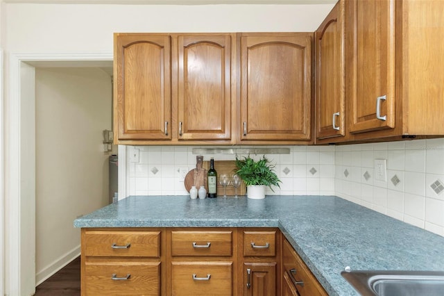 kitchen featuring baseboards, backsplash, and brown cabinets